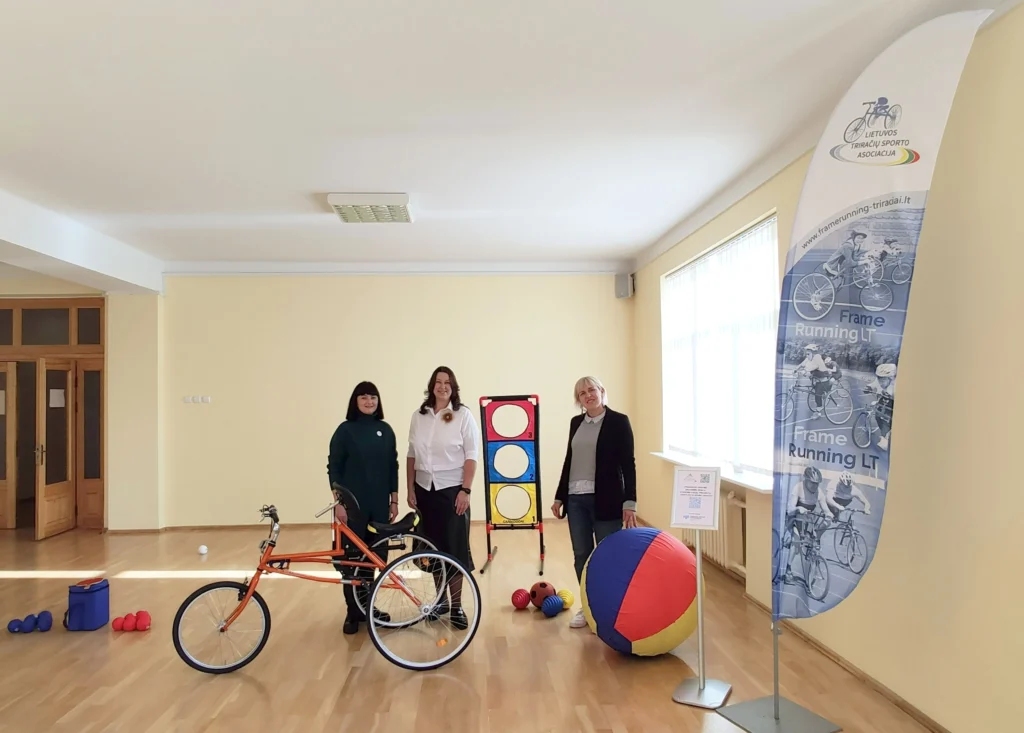 A group of people standing in a room with a bicycle and toys